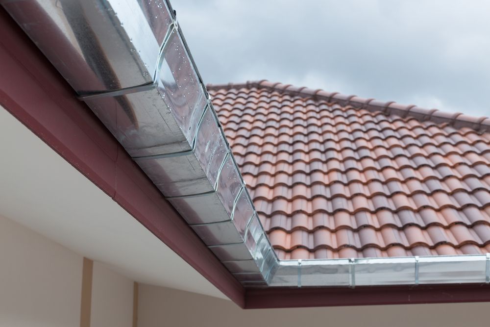 Close-Up of A House Roof with Red Tiles and Shiny Metal Rain Gutters — All-Clear Gutter Guard NQ in Smithfield, QLD