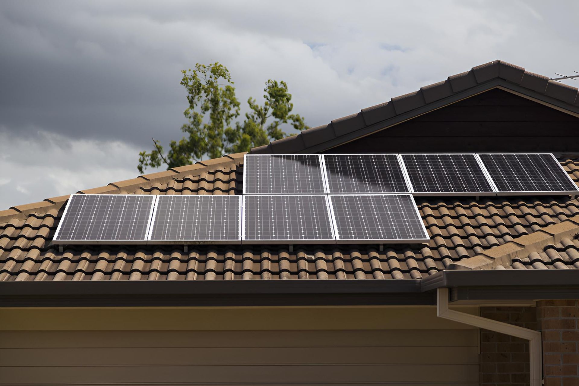Solar Panels on A Brown Tiled Roof of A House Under a Cloudy Sky — All-Clear Gutter Guard NQ in Babinda, QLD