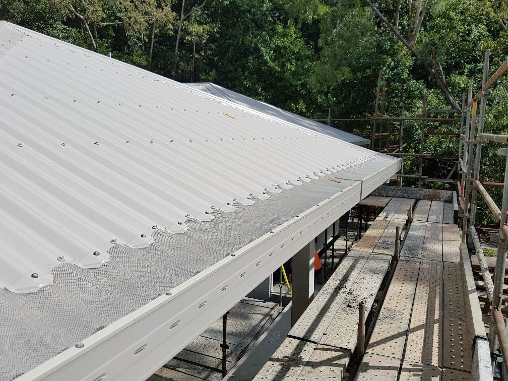 Gray Corrugated Metal Roof with Gutter, Scaffolding, and Trees in Background — All-Clear Gutter Guard NQ in Bentley Park, QLD