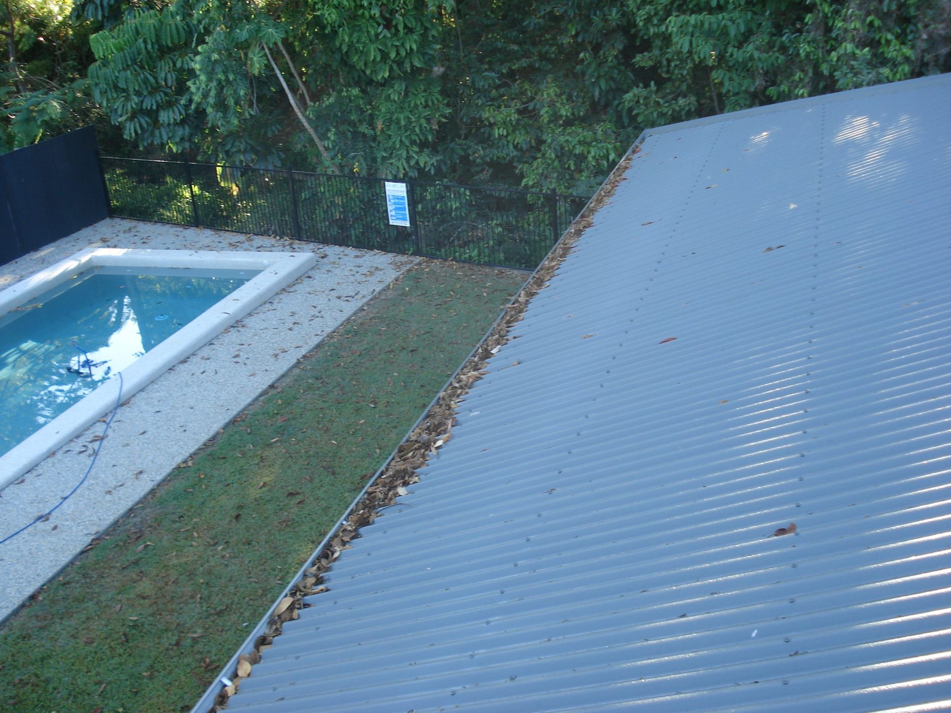A View from A Roof Showing a Pool, Lawn, and Trees Beyond. the Roof Is Metallic Gray — All-Clear Gutter Guard NQ in Atherton, QLD