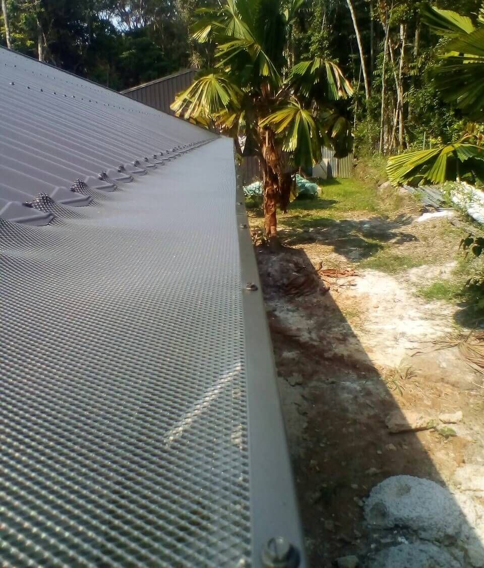 A Roof With a Fence Surrounding It and Trees in the Background  — All-Clear Gutter Guard NQ in Cairns, QLD