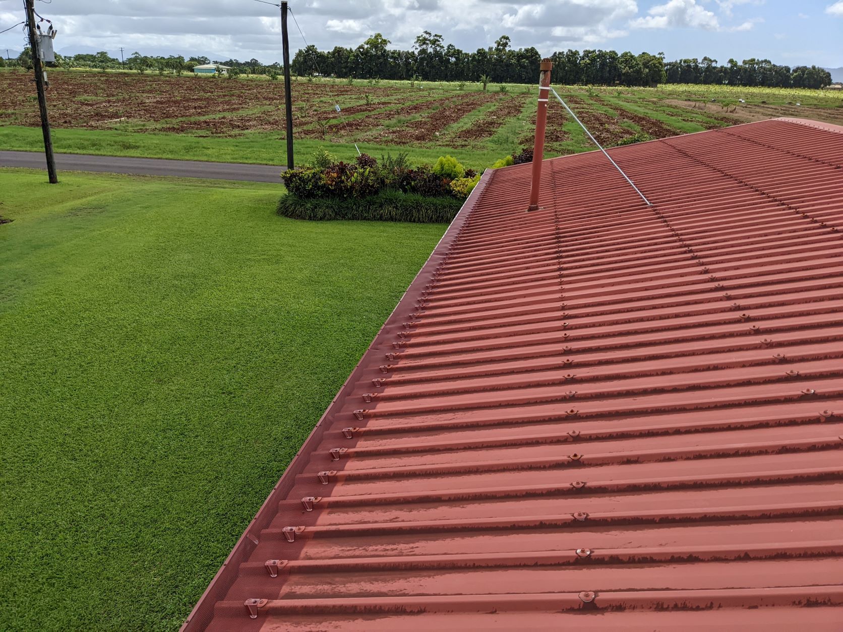 A Red Roof is Sitting on Top of a Lush Green Field — All-Clear Gutter Guard NQ in Tablelands, QLD