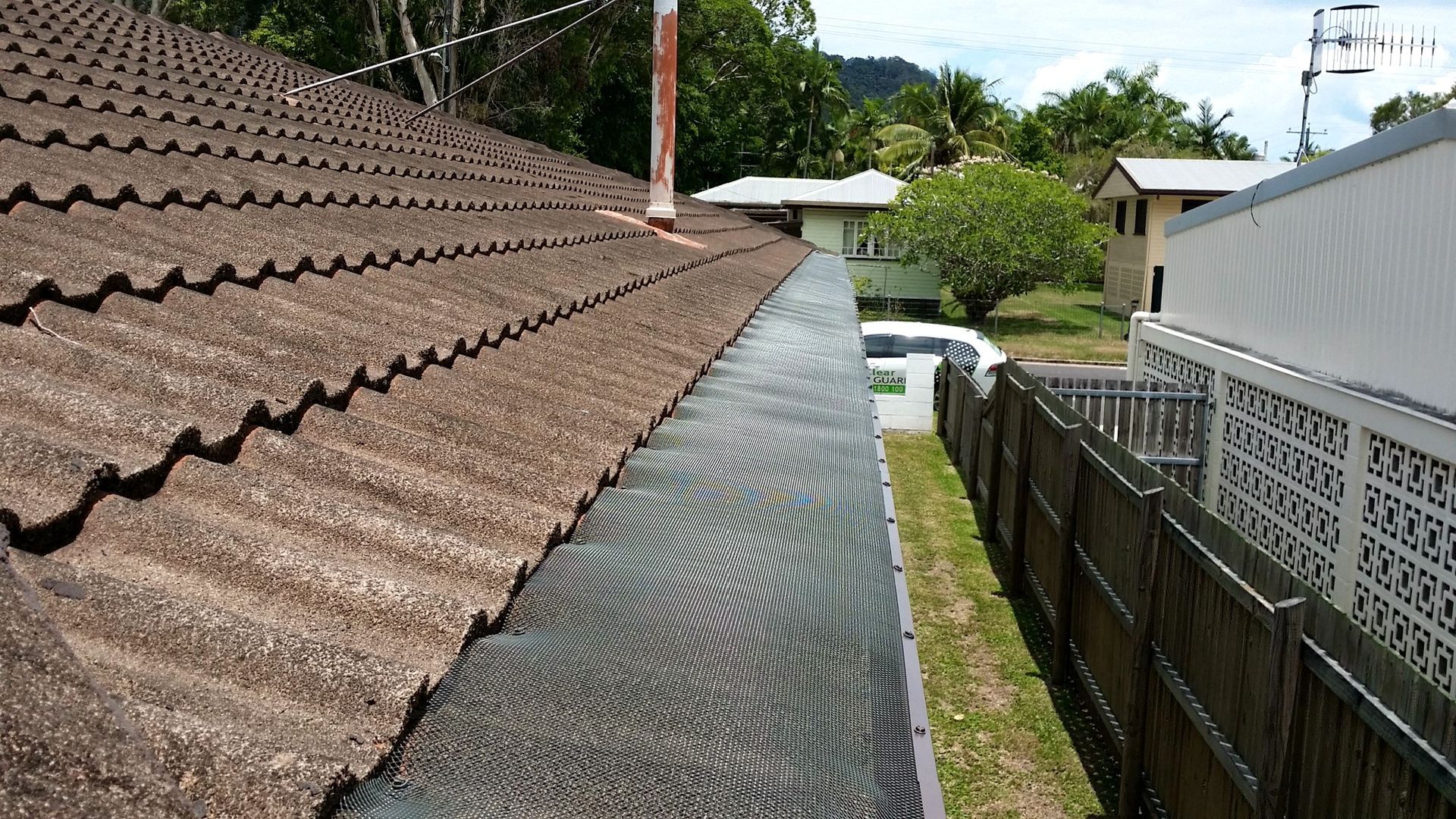 A gutter on the roof of a house next to a fence — All-Clear Gutter Guard NQ in Cairns, QLD