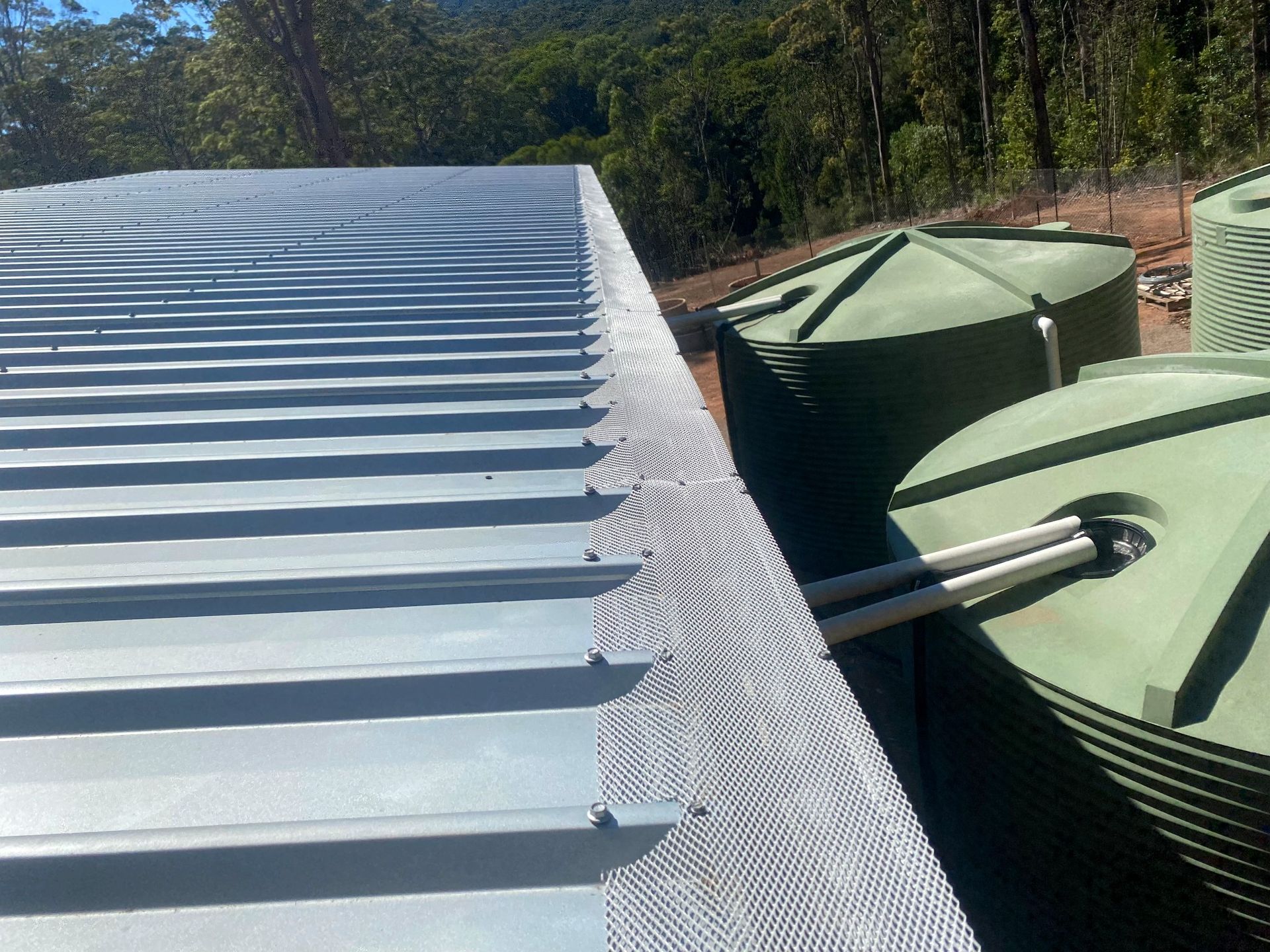 A roof with a gutter and water tanks on it — All-Clear Gutter Guard NQ in Cairns, QLD