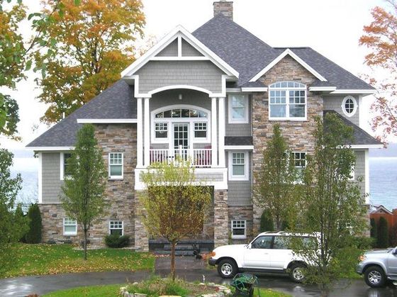 A white suv is parked in front of a large house
