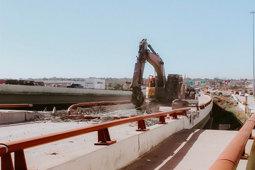 A large excavator is being used to demolish a bridge