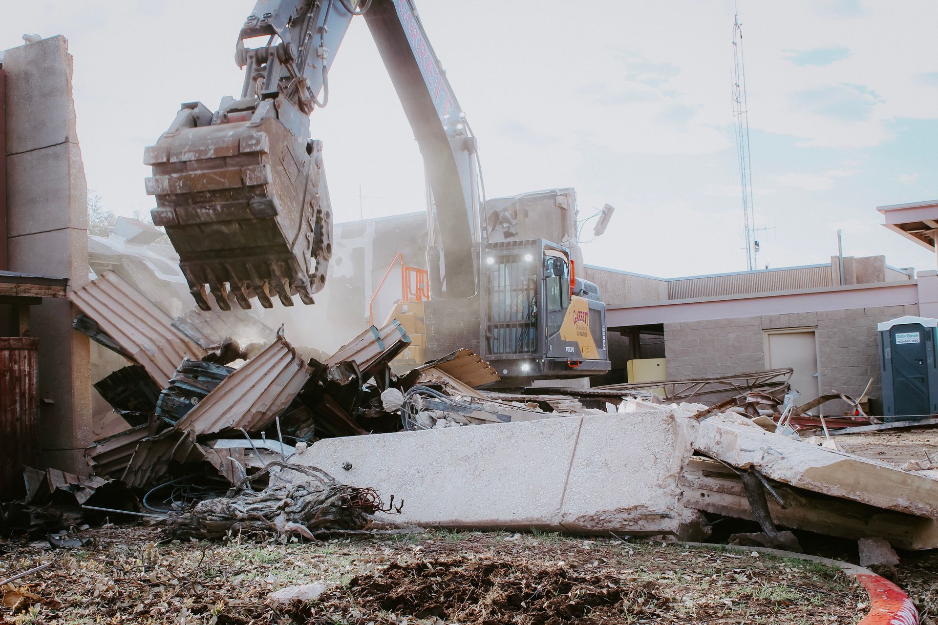 A large excavator is demolishing a building on a construction site.