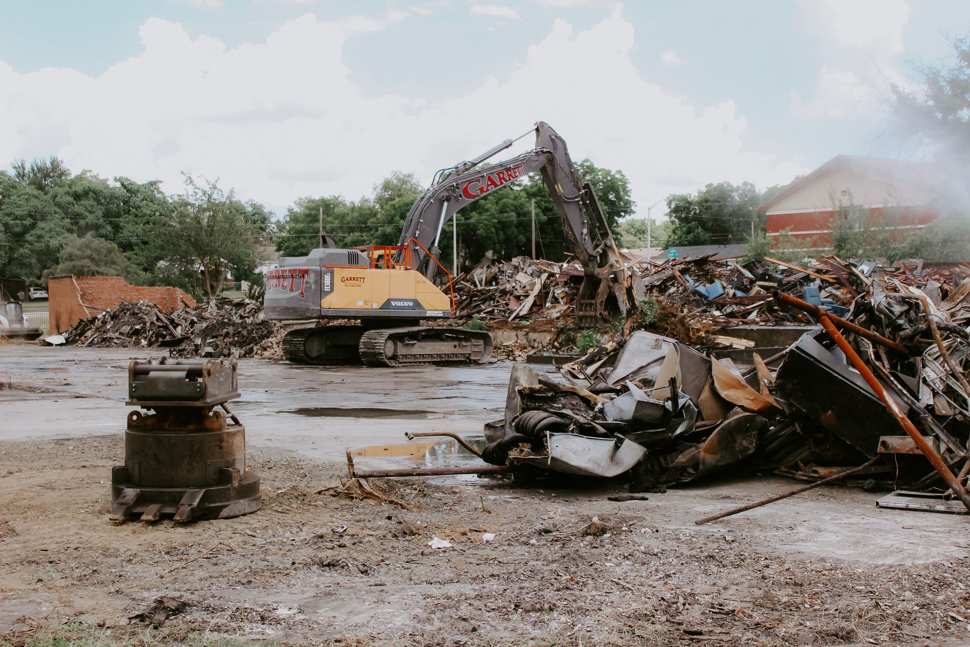 A bulldozer is destroying a building in a field.
