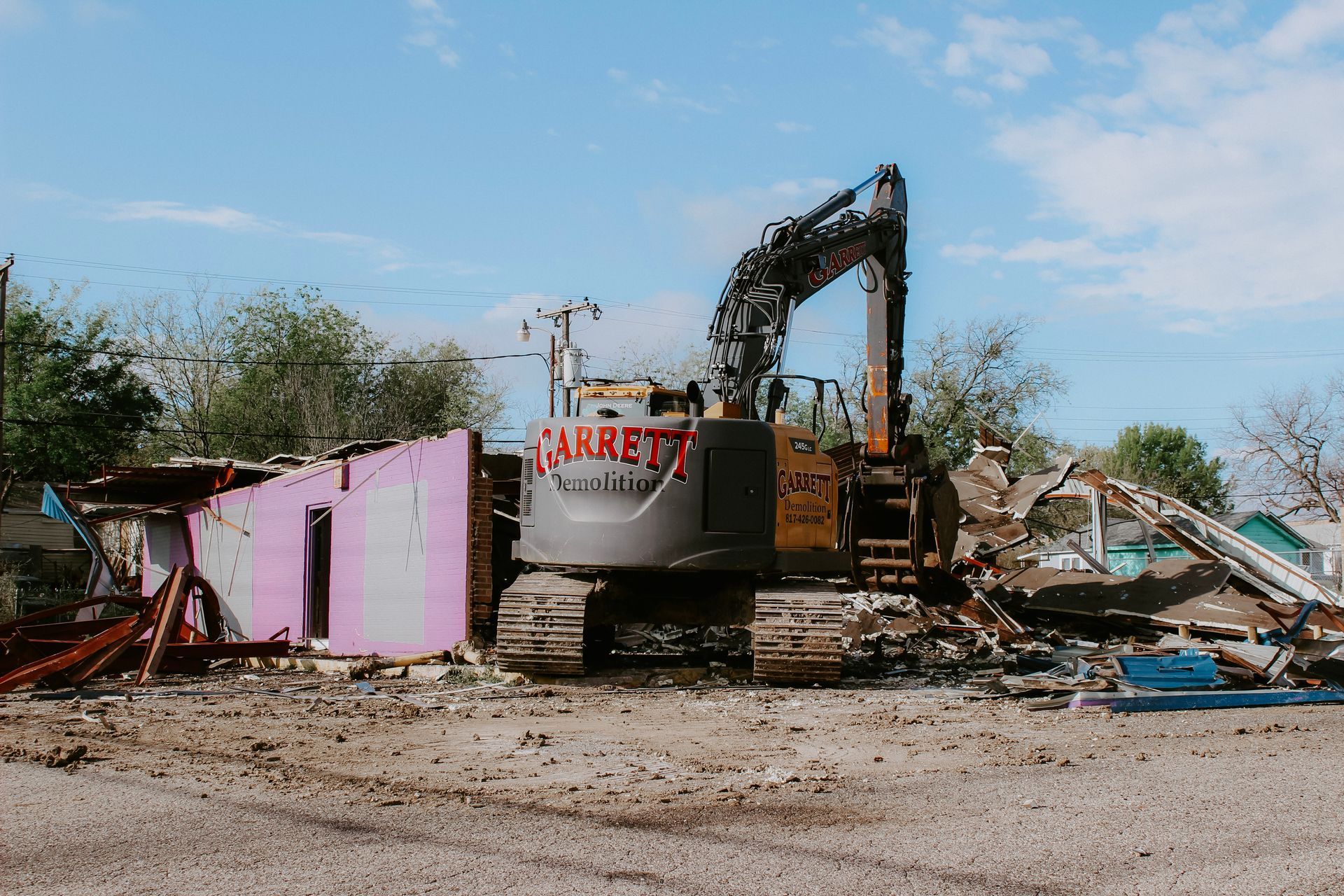 A large excavator is demolishing a building in a dirt field.