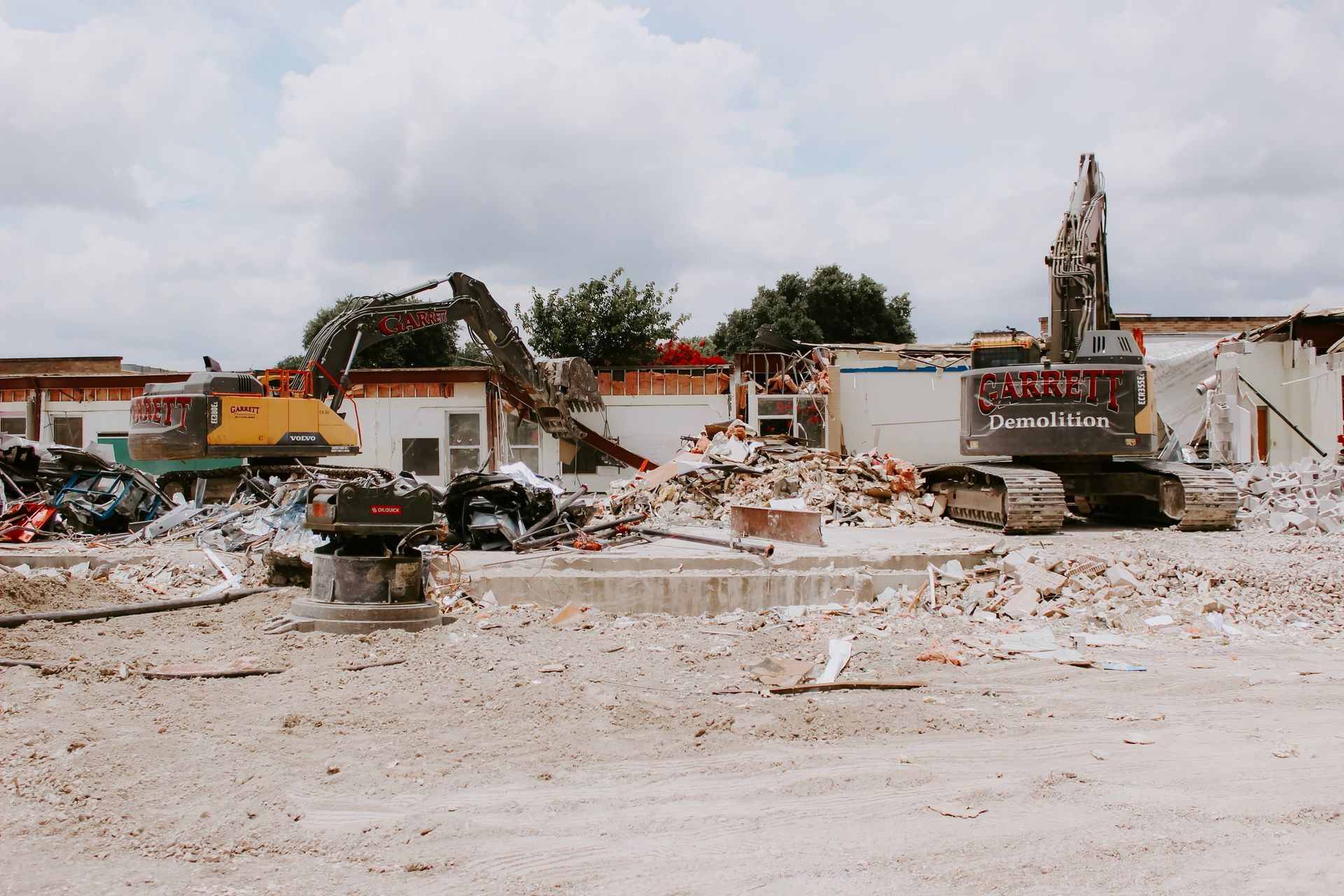 A large excavator is demolishing a building on a construction site.