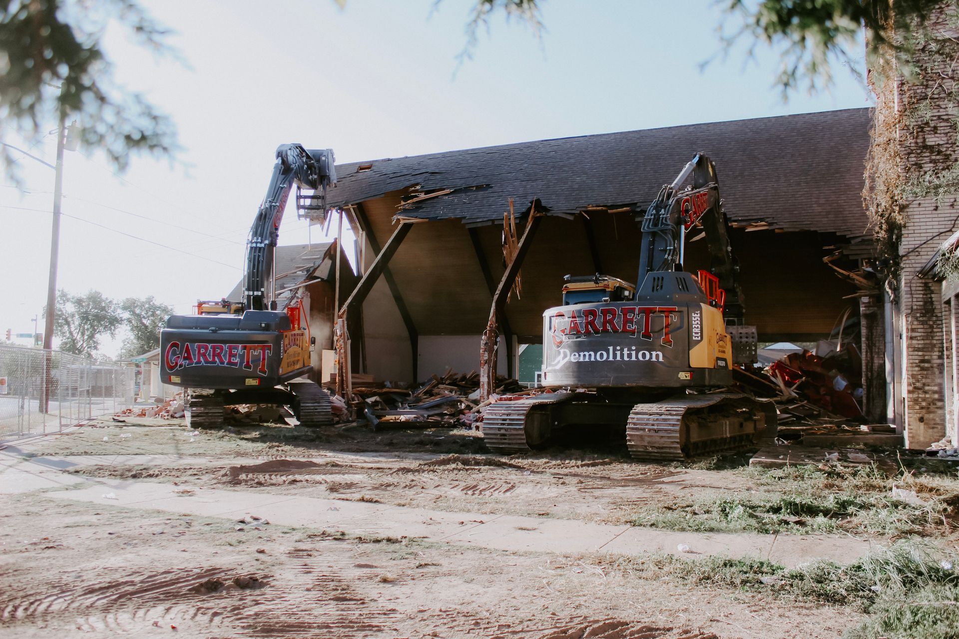 Two excavators are working on a building that is being demolished.