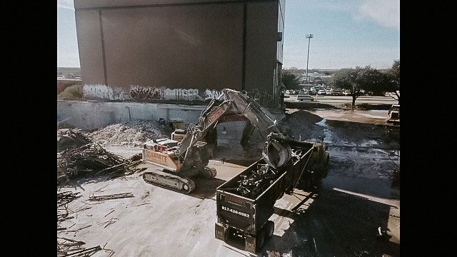 a large excavator is loading a dumpster on a construction site .