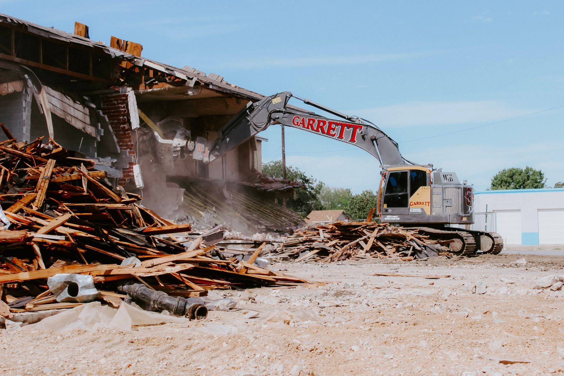 A large building is being demolished by a large excavator.