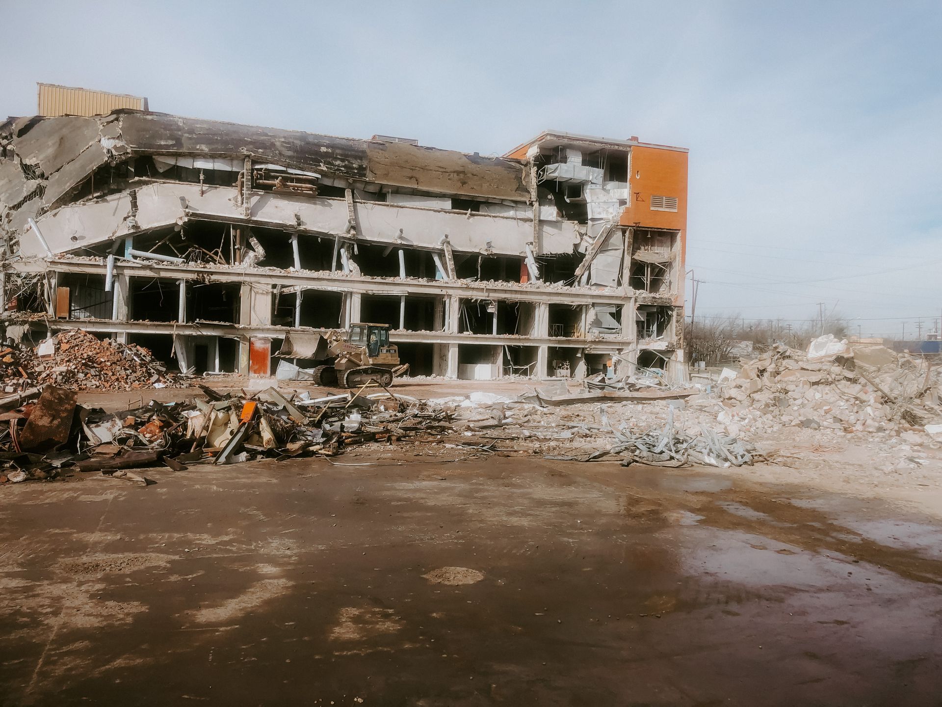 A large building is being demolished in a field.