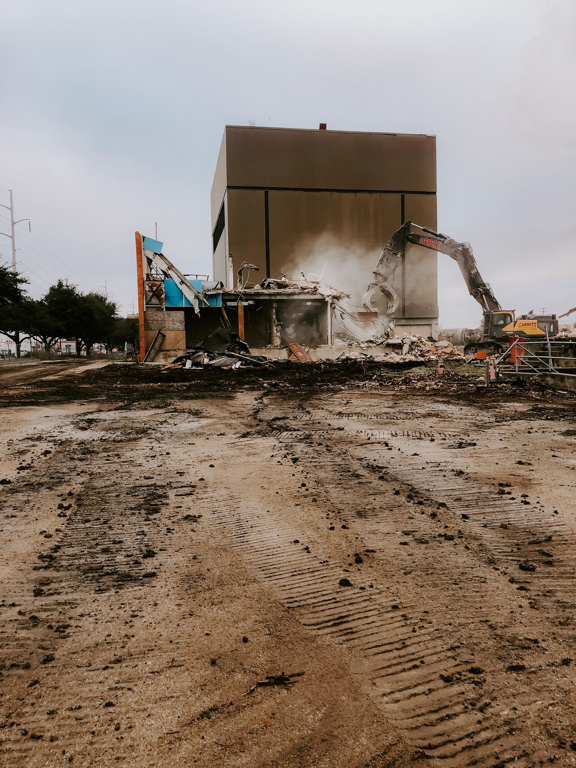 A large building is being demolished by a large excavator.