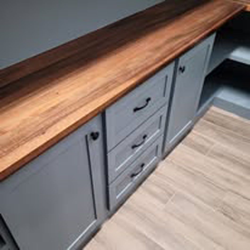 A kitchen with white cabinets and a wooden counter top.