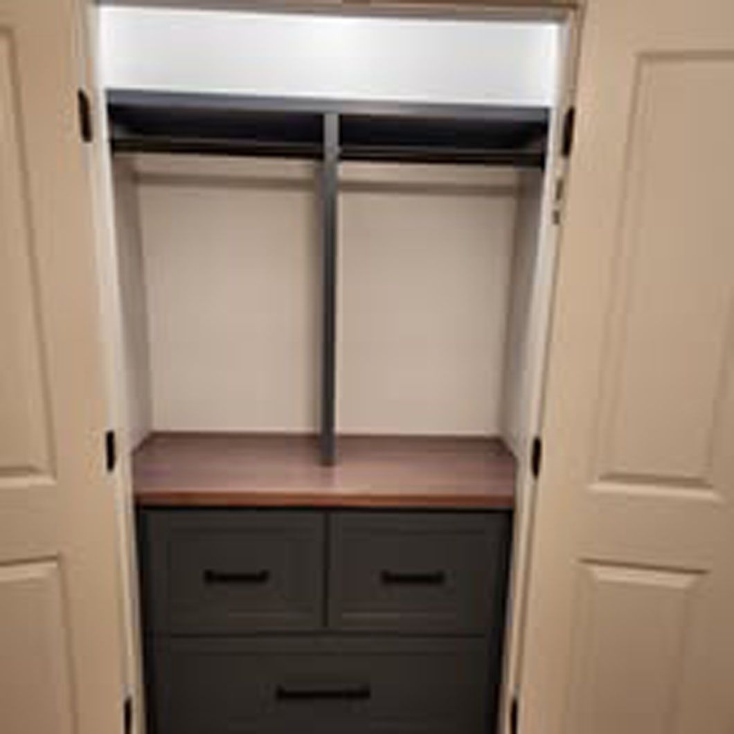 A closet with drawers and a shelf in it.