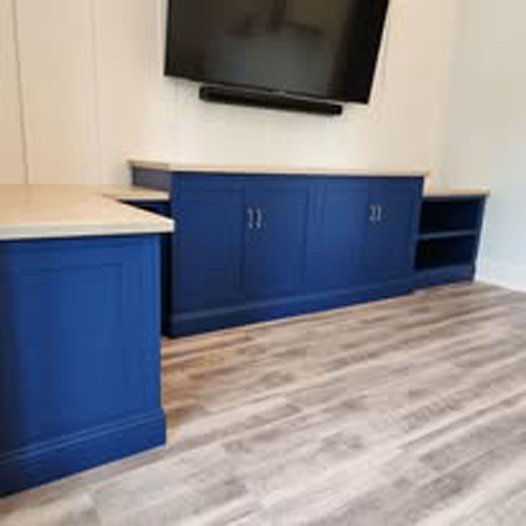 A living room with blue cabinets and a flat screen tv on the wall.