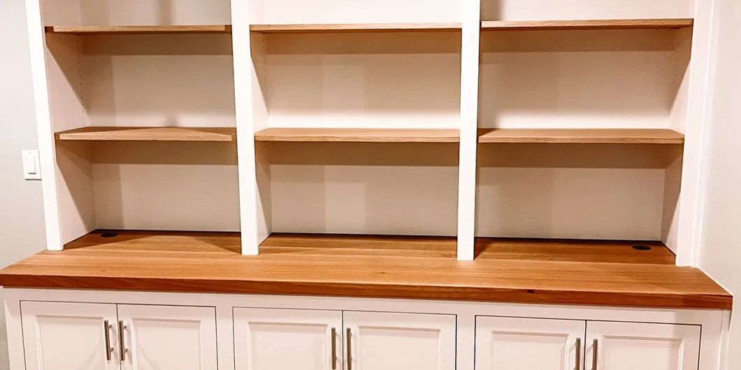 A white cabinet with wooden shelves and drawers in a room.