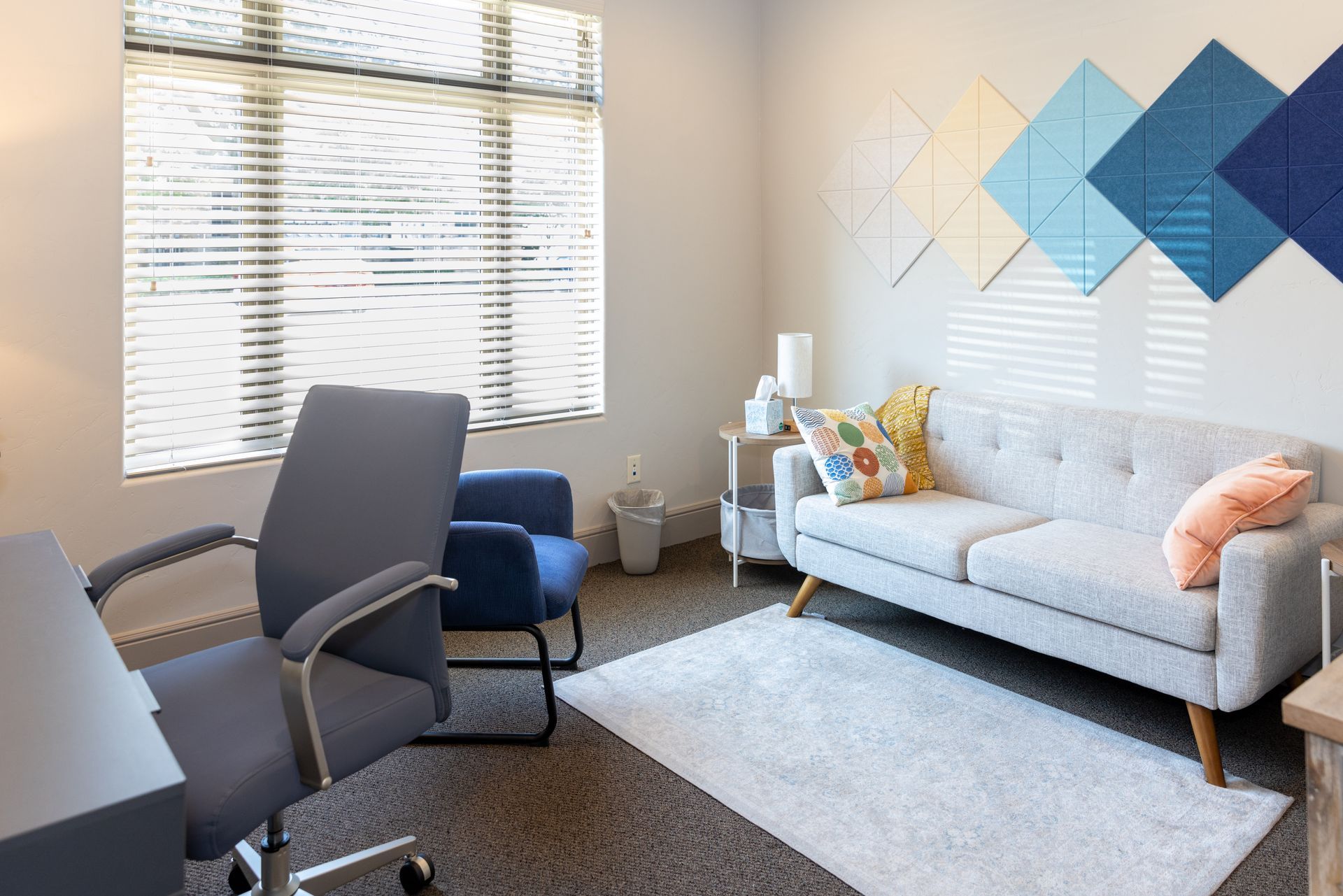 A living room with a couch , chair , desk and window.