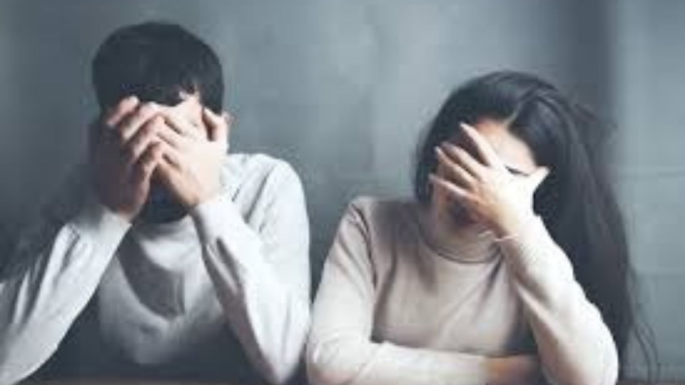 Two people sitting, both covering their faces with their hands, looking distressed struggling with communication.