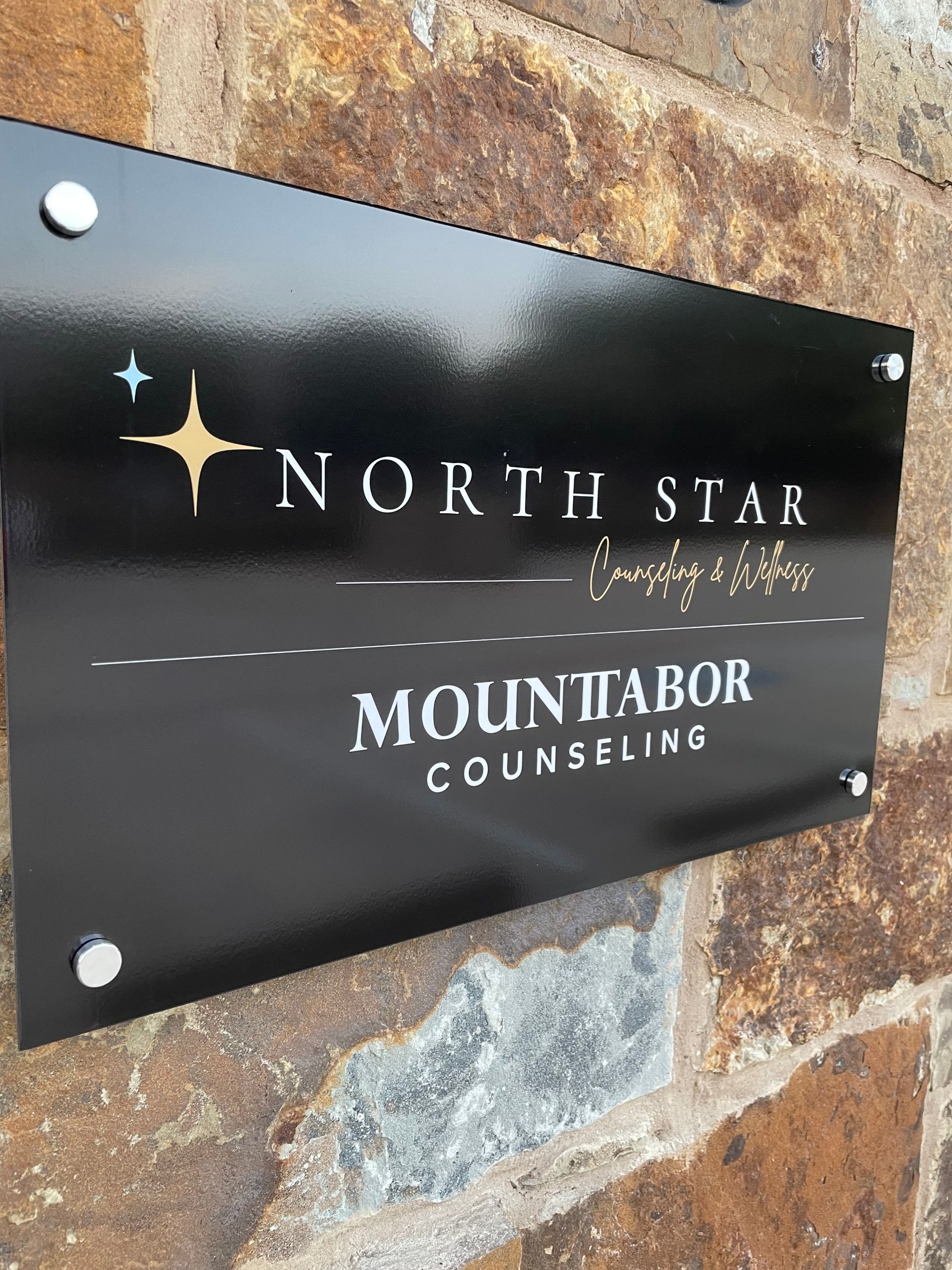 A black sign on a brick wall that says north star mountabor counseling