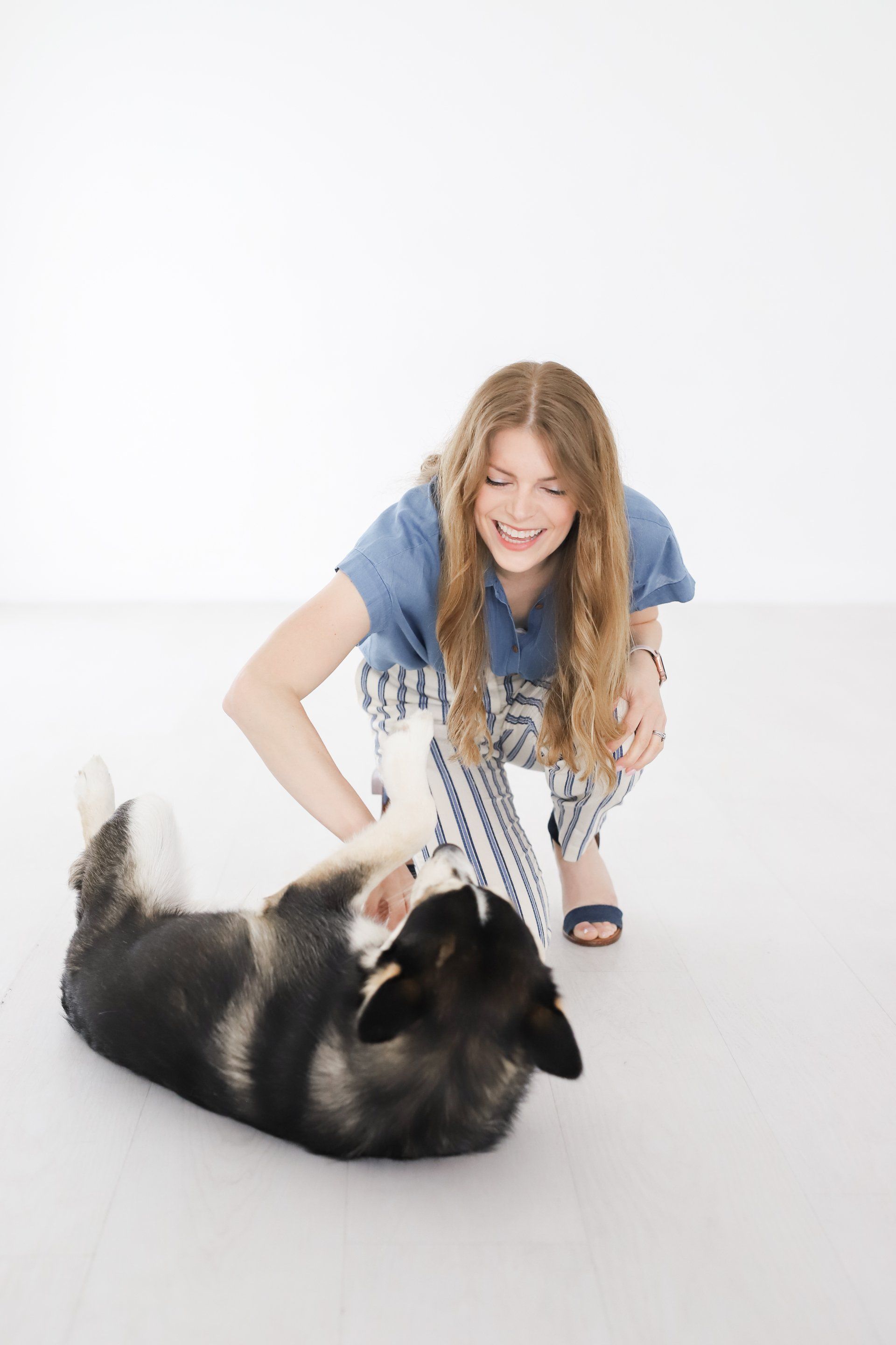 A woman is kneeling down next to a dog on the floor as part of trauma counseling in Texas. 