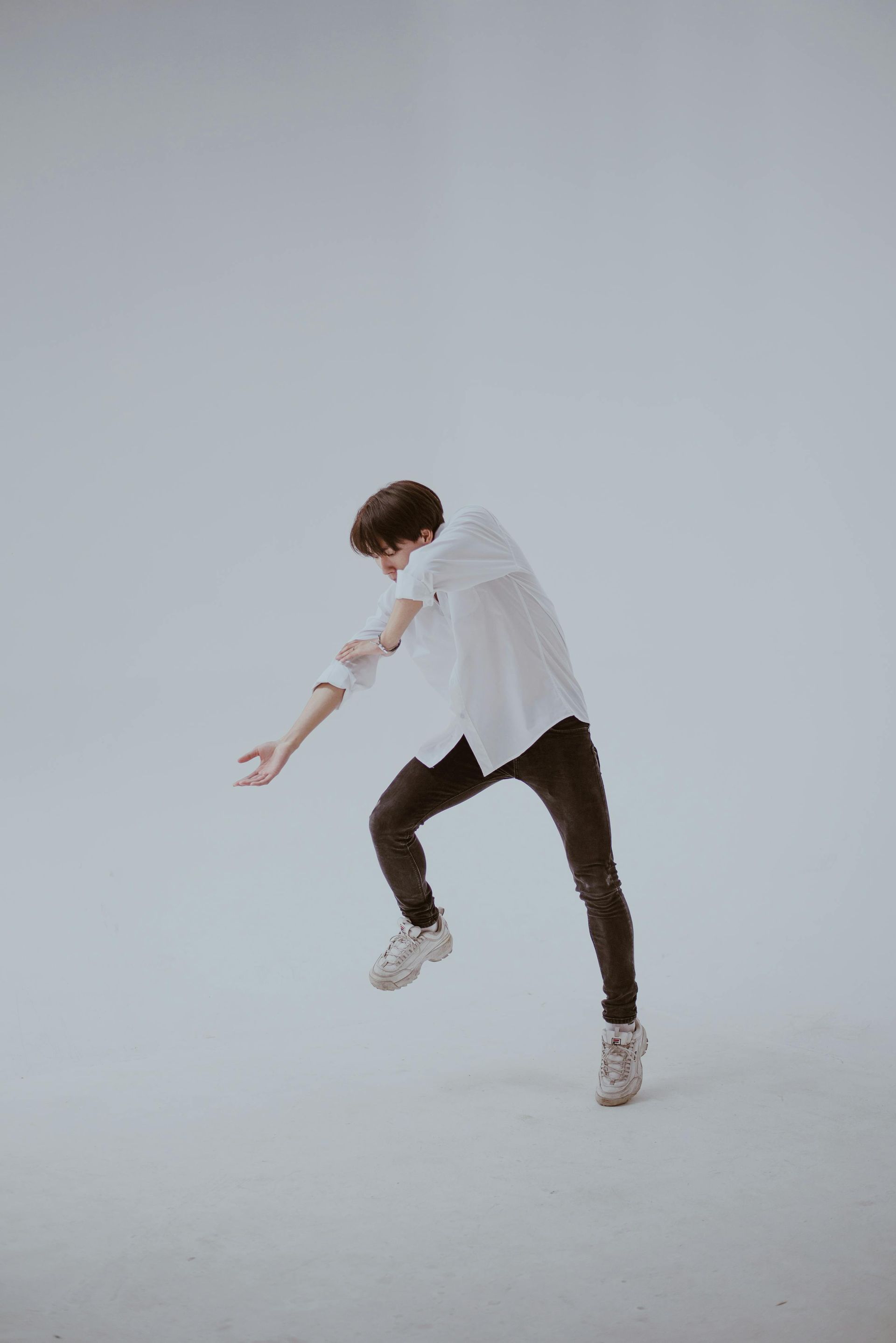 A man in a white shirt and black pants is dancing on a white background doing dance therapy in dfw