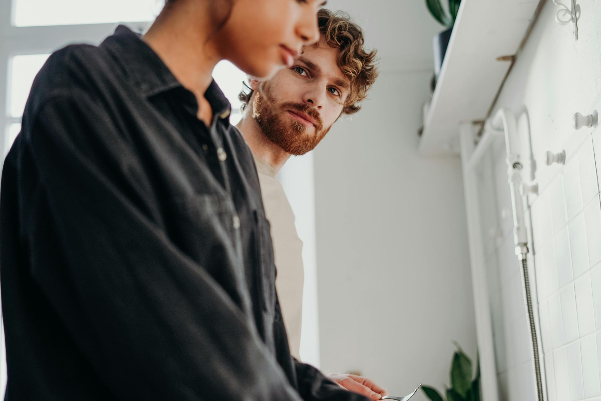 A person in a black shirt and a person with red hair stare towards a bright window using emotion focused therapy
