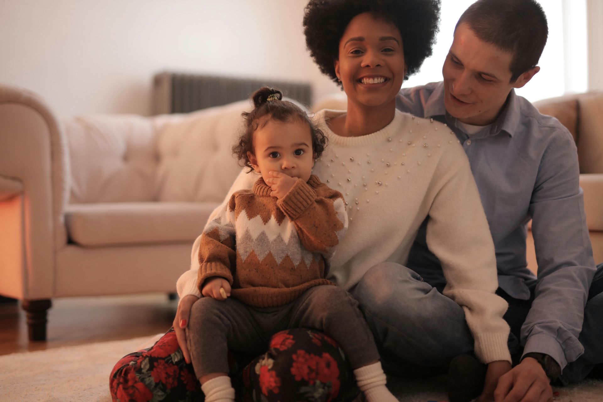 A man and woman are sitting on the floor with a baby attending multicultural family counseling in Grapevine TX.