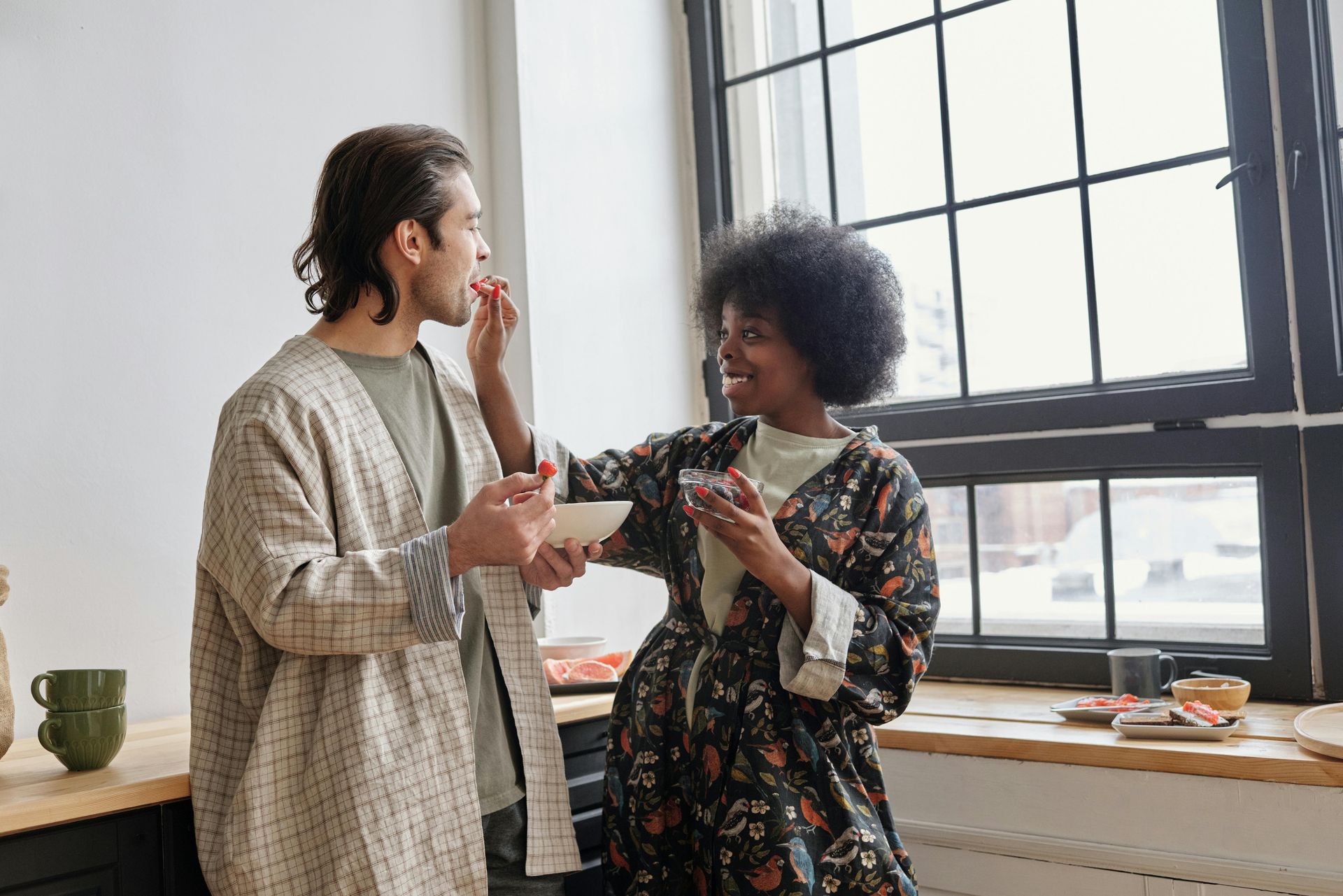 Woman feeds man fruit; kitchen setting connecting after couples counseling.