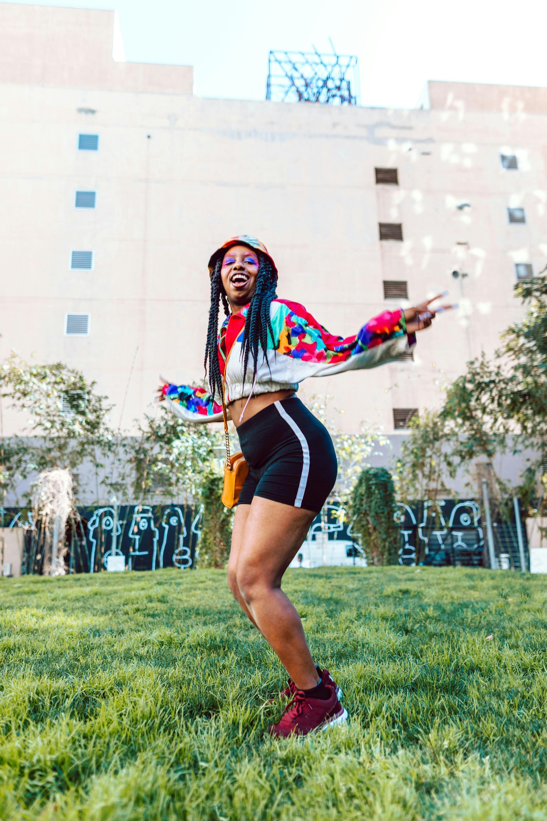 A woman is standing in the grass in front of a building doing dance therapy in dfw