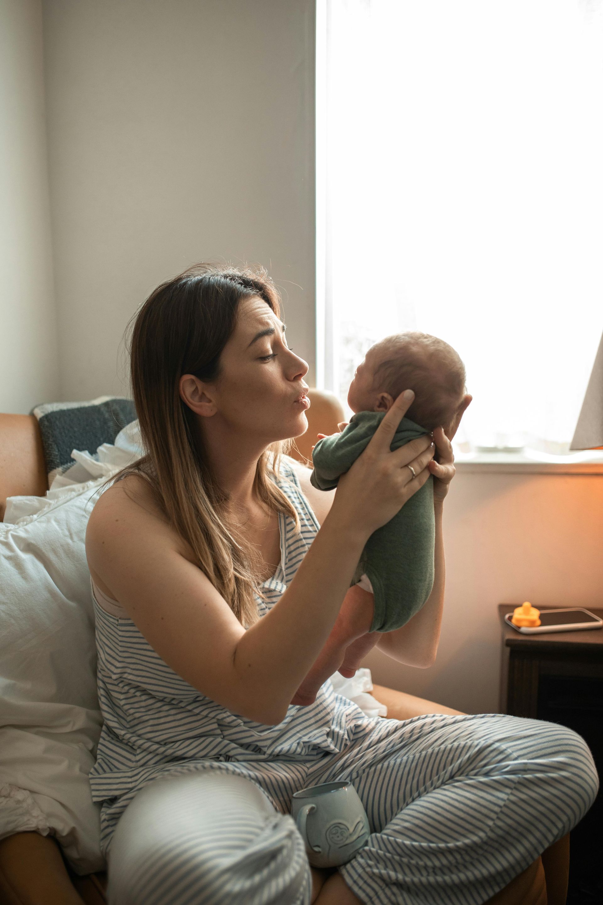 A woman is sitting in a chair holding a newborn baby.