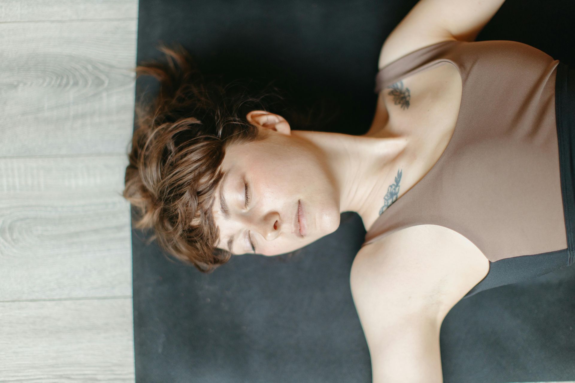 A woman is laying on a yoga mat with her eyes closed practicing restorative yoga at a therapy healing retreat in Grapevine Texas.