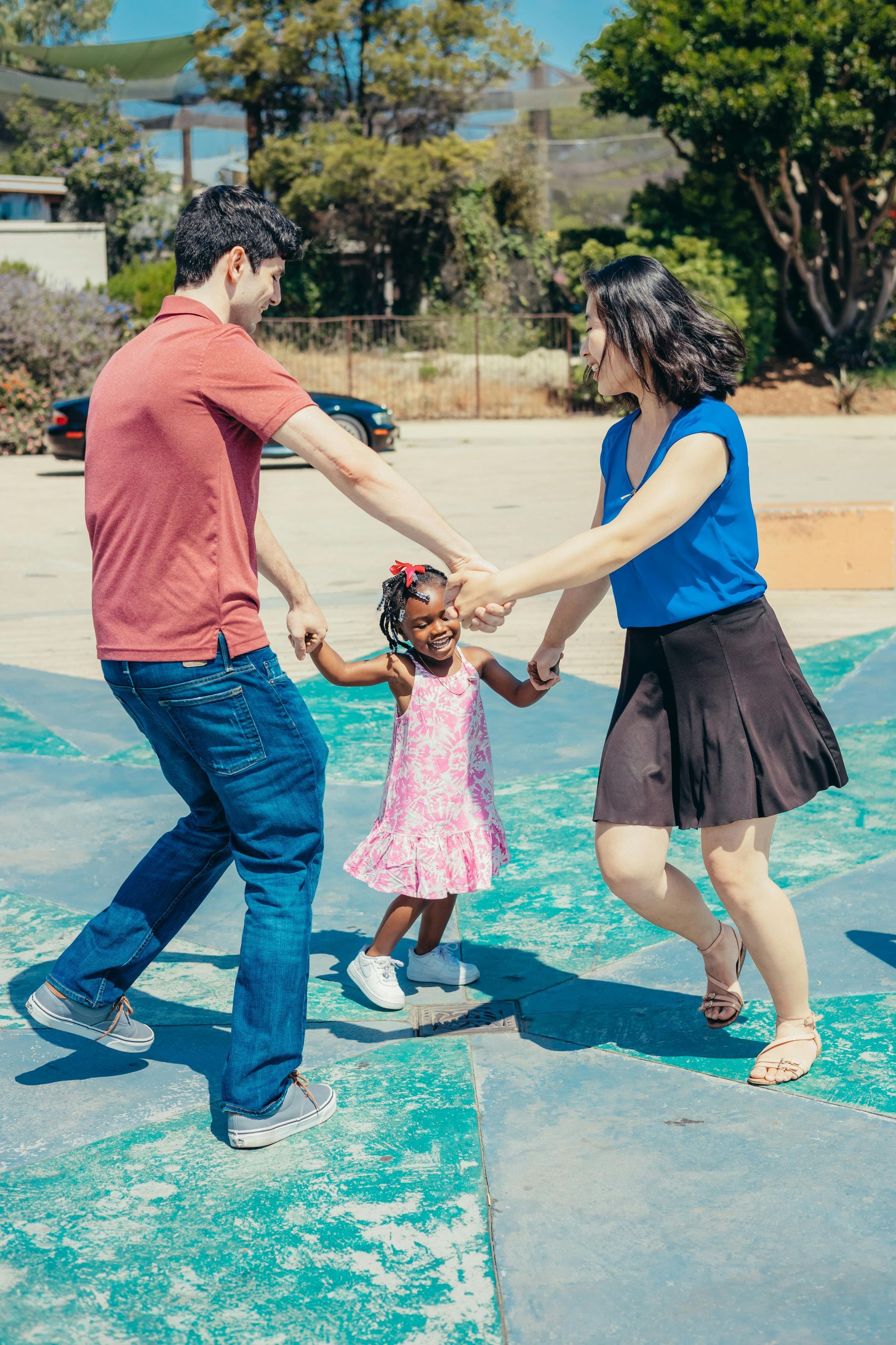 A man and woman are holding hands with a little girl in a park participating in dance movement therapy in Grapevine Texas