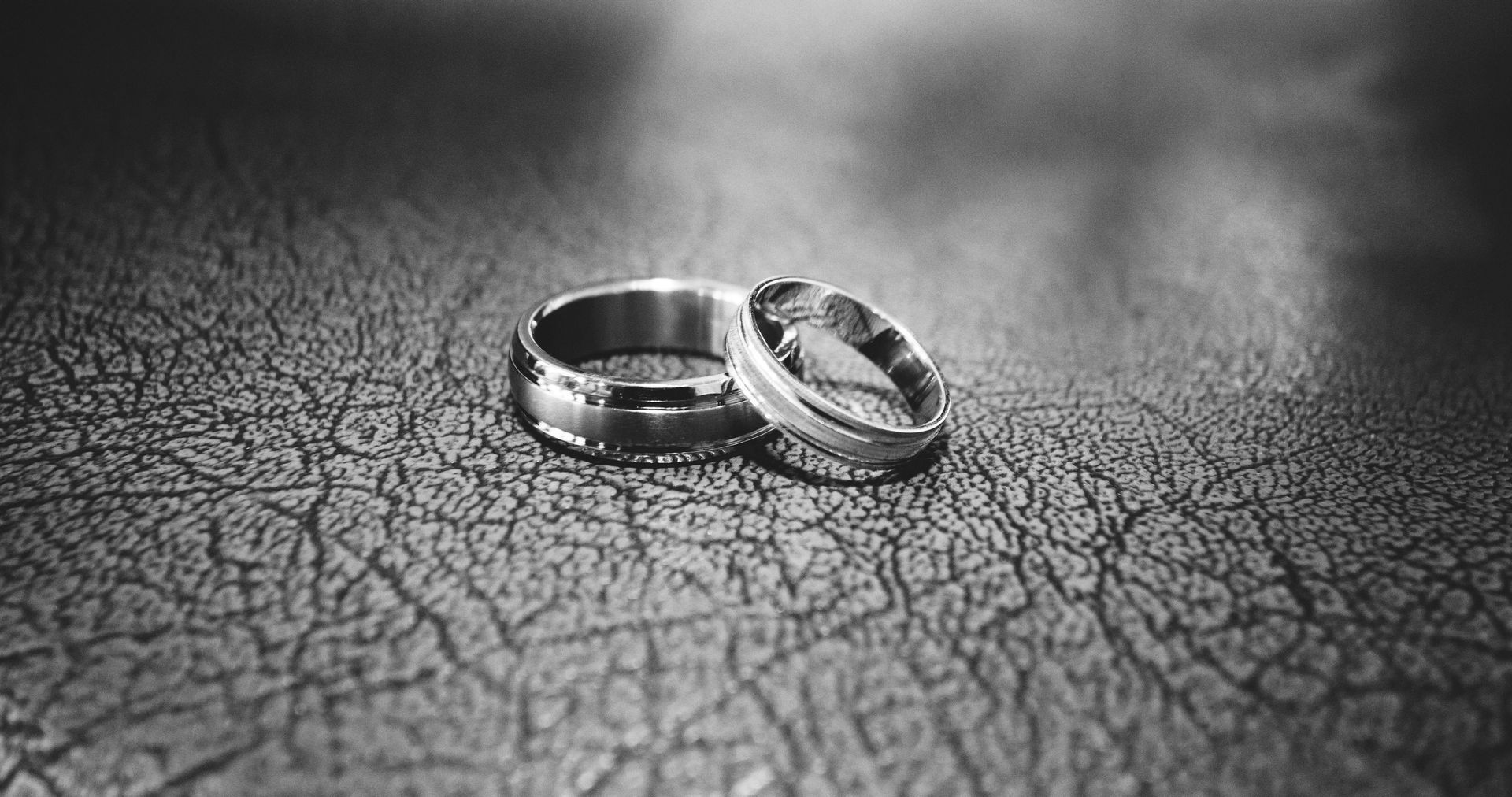 Two wedding rings are sitting on a cracked surface.