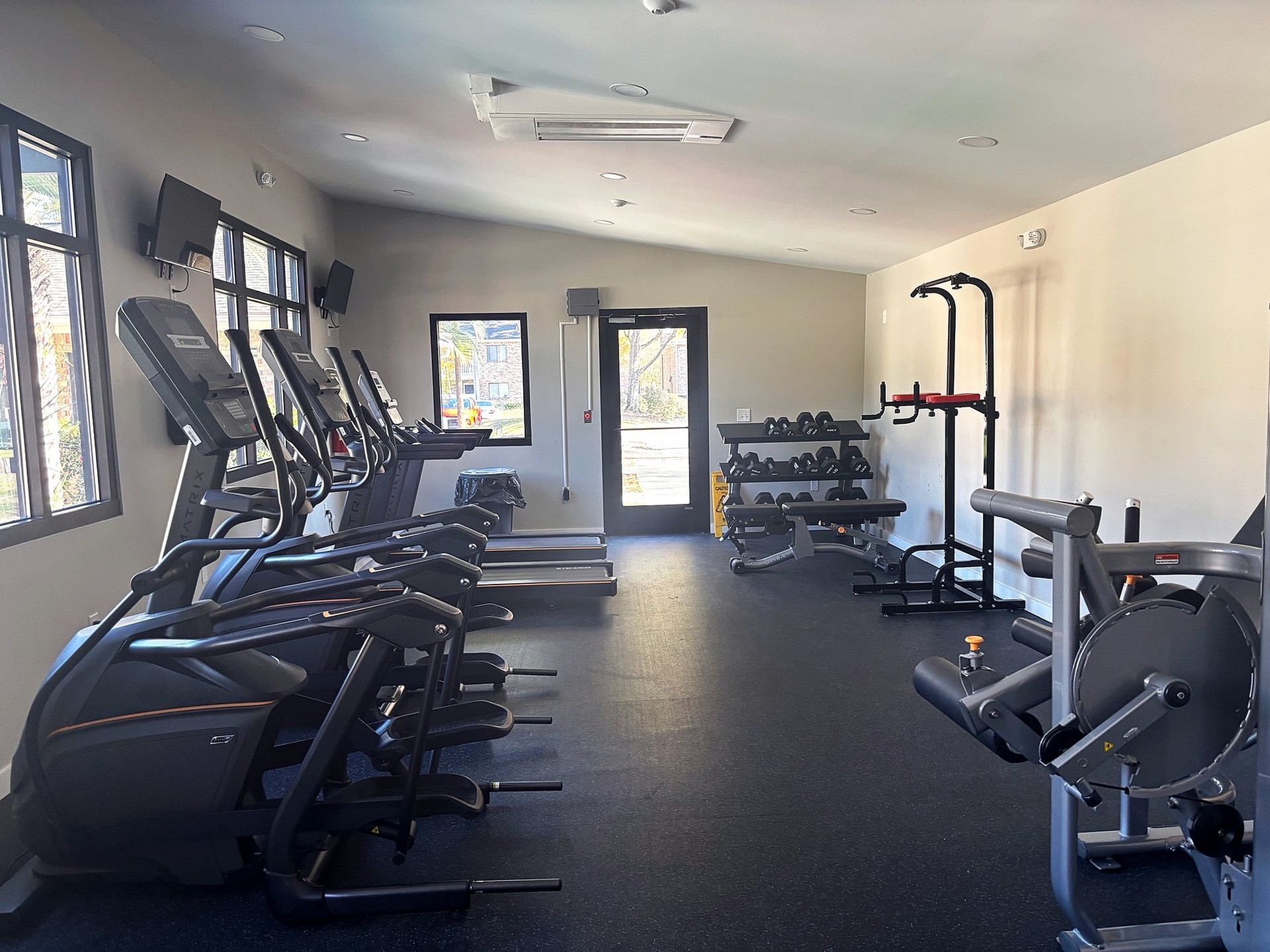 Interior fitness center with treadmills, dumbbells, and weight machines.