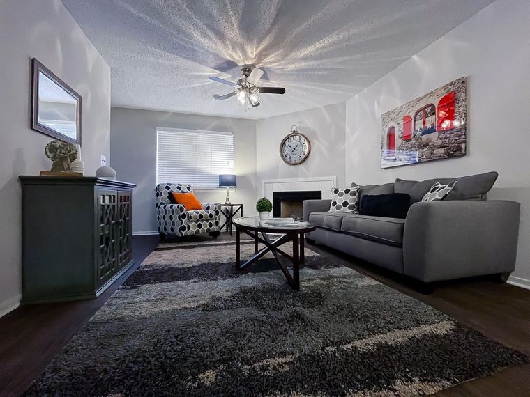 Cozy living room with a gray sofa, patterned armchair, coffee table, fireplace, and wall art.