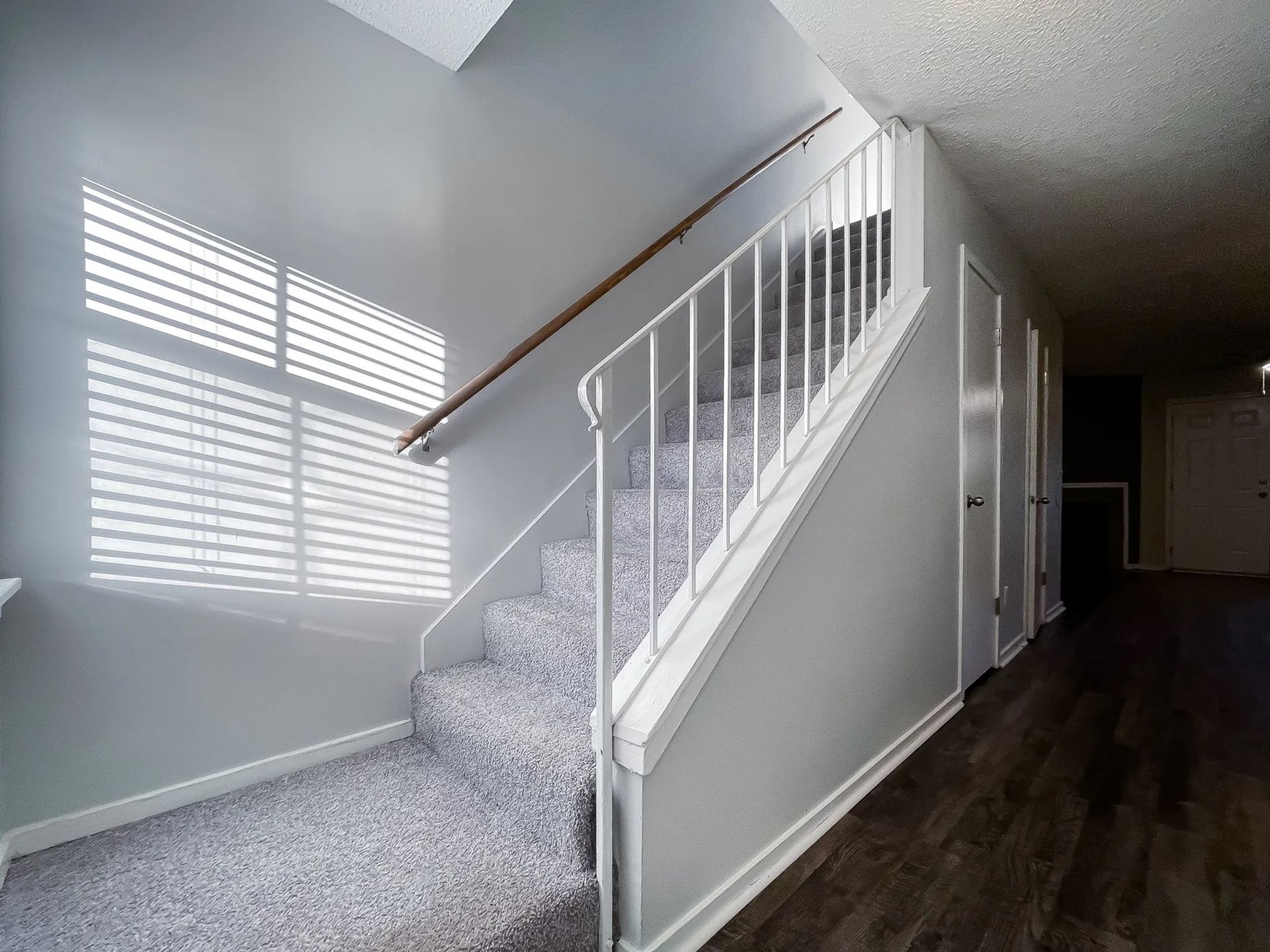 Interior stairwell with carpeted stairs, white railing, and hallway.