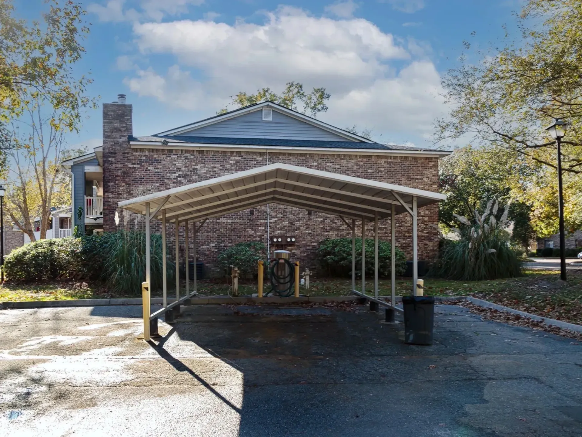 Carport area with green plants and a brick building in the background at Plantation Flats in North Charleston, SC.