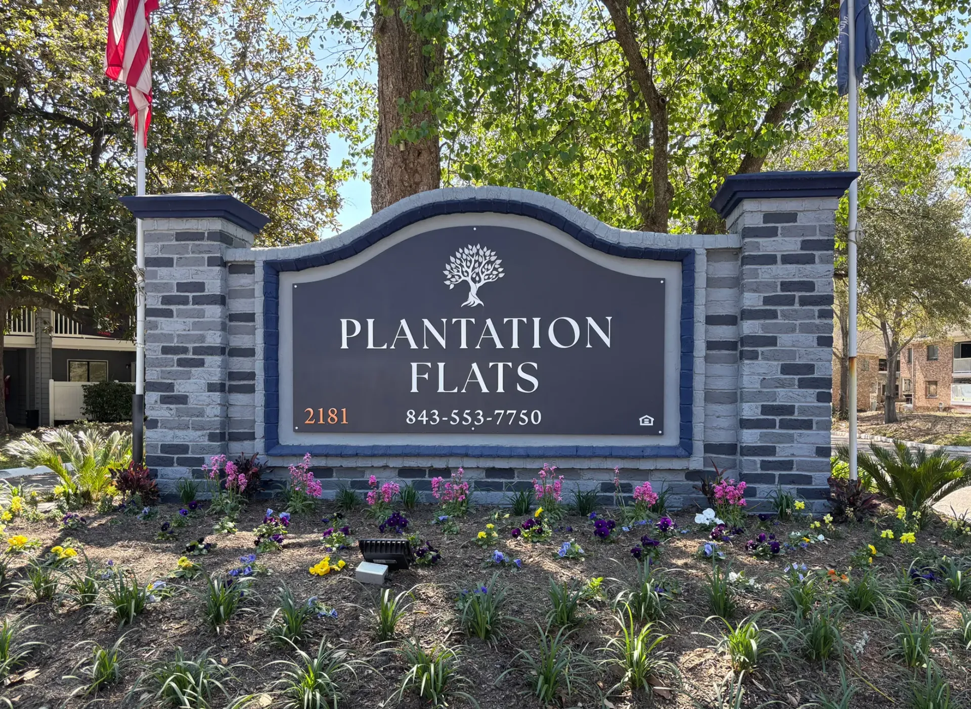 Signage for Plantation Flats with flowers in front in North Charleston, SC.