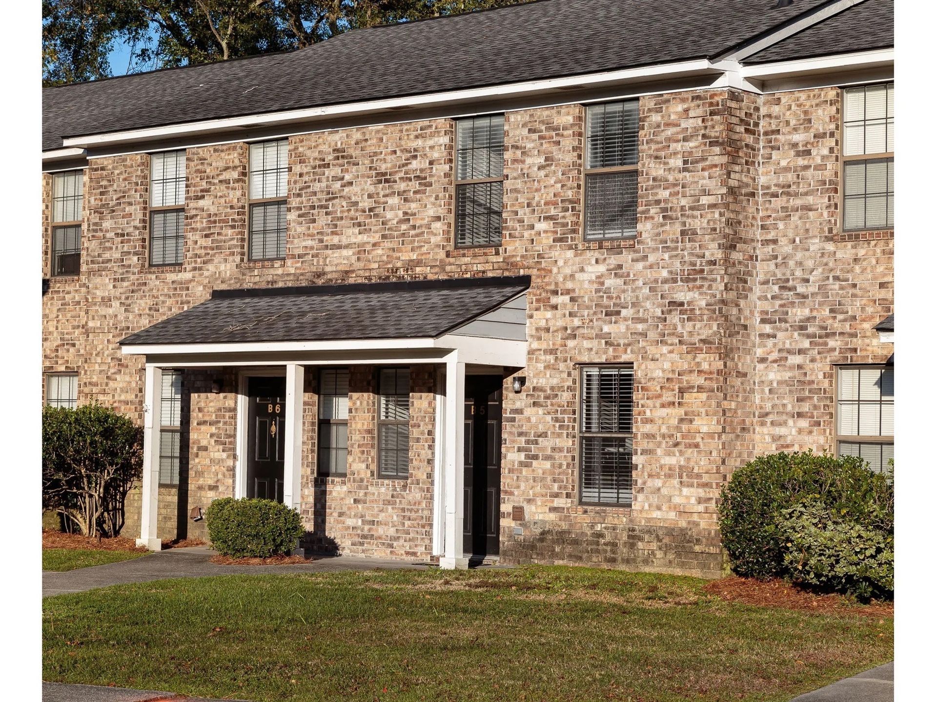 Exterior view of a brick apartment building entrance with a small covered porch.