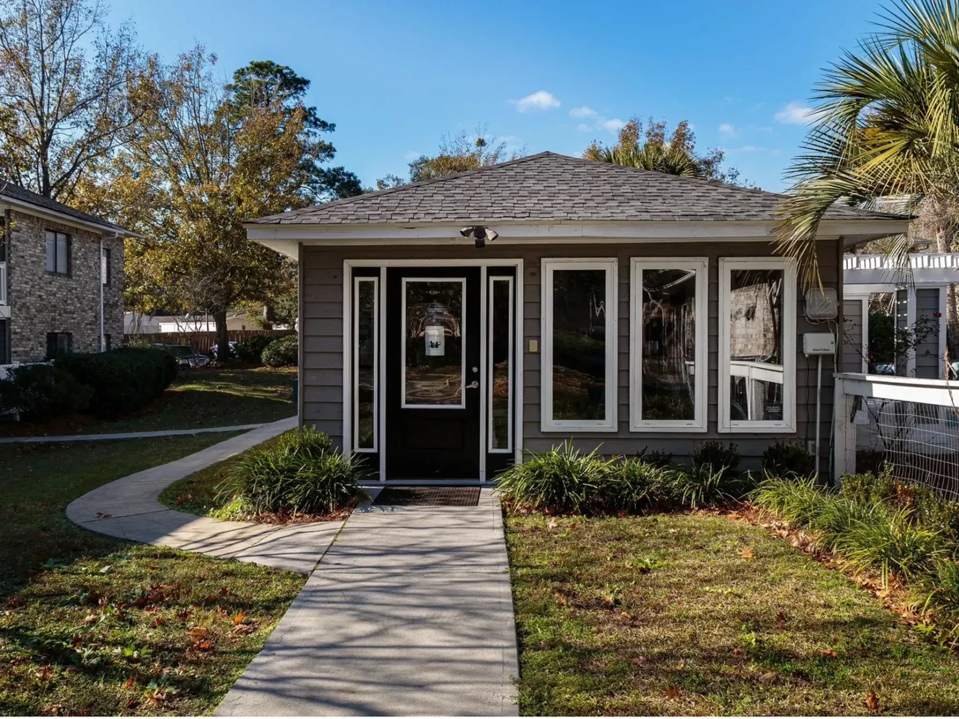 Exterior view of a building entrance with landscaped pathway and windows at Plantation Flats in North Charleston, SC.