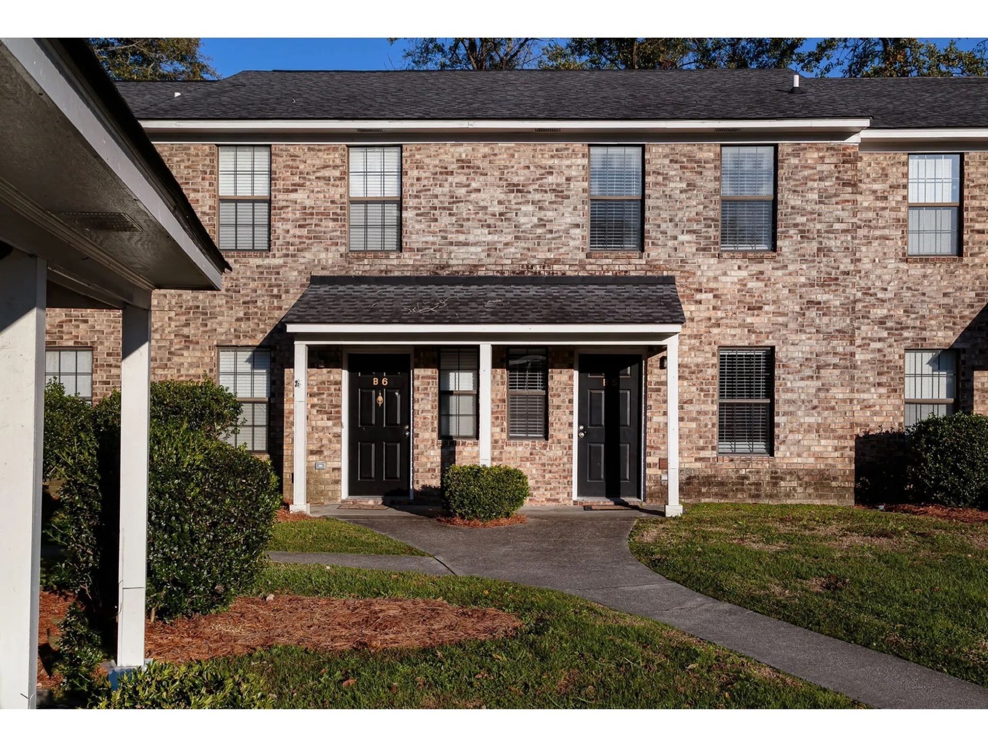 Brick exterior of a two-unit apartment building with a shared covered entry.