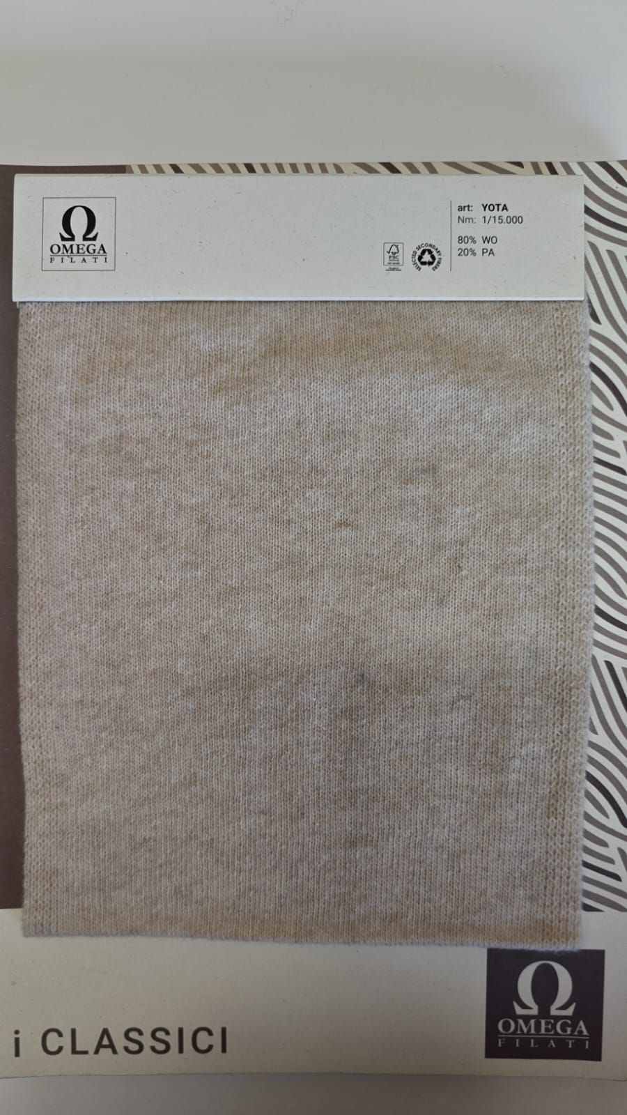 Muestra de tela con el logotipo de Omega Classics. La tela es de color marrón claro con una superficie texturizada 