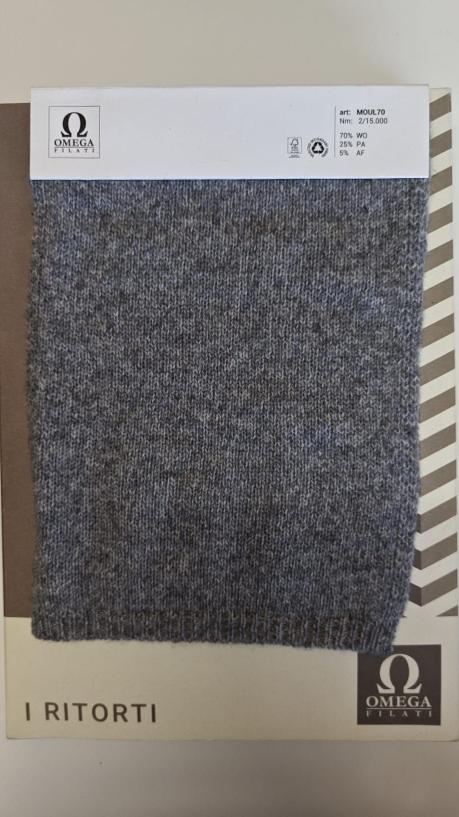 Muestra de tejido de punto gris con etiqueta blanca que incluye el logotipo y el texto de la marca.