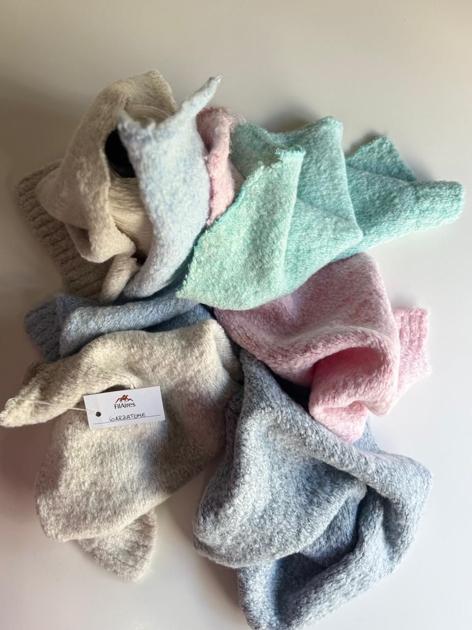 Montón de cuadrados de punto de colores pastel, posiblemente paños o toallitas.