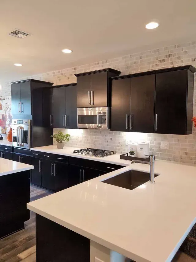 A kitchen with black cabinets and white countertops.