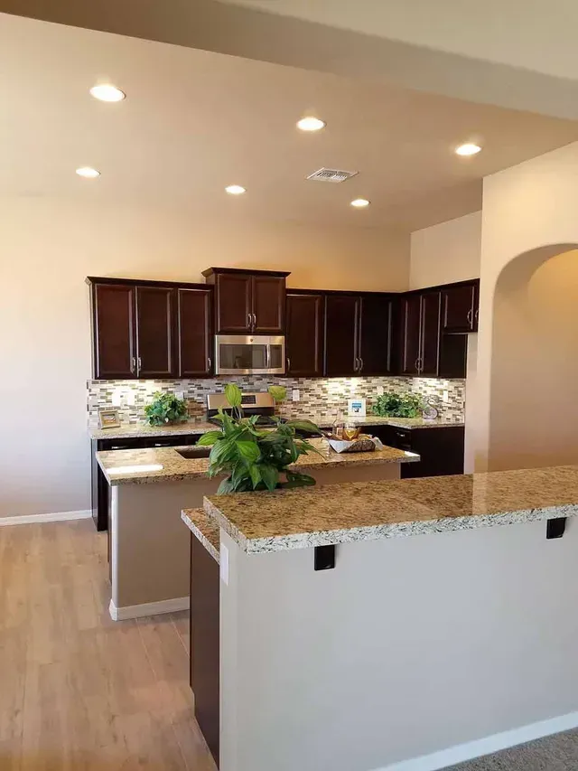 A kitchen with granite counter tops , stainless steel appliances , and brown cabinets.