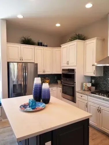 A kitchen with white cabinets , stainless steel appliances , and a large island.